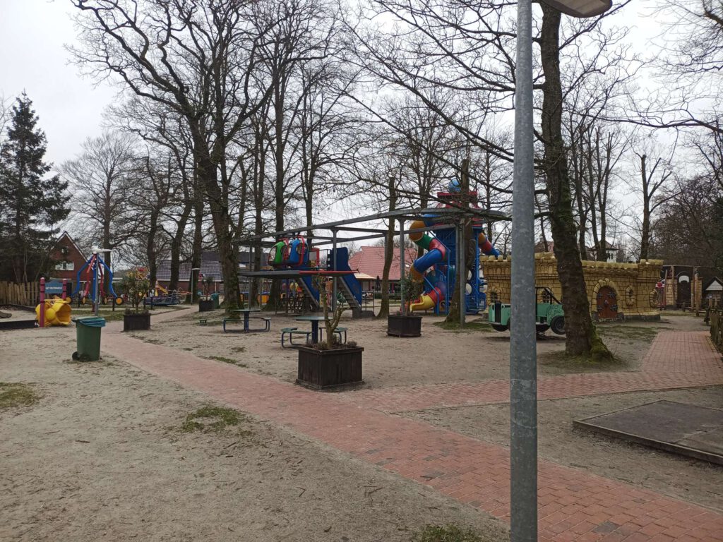 Het speelterrein van Sprookjeshof Zuidlaren buiten, met diverse speeltoestellen in diverse kleuren, zoals een hangende monorail met helicopters, een glijbanen, klimtoestellen en wips.